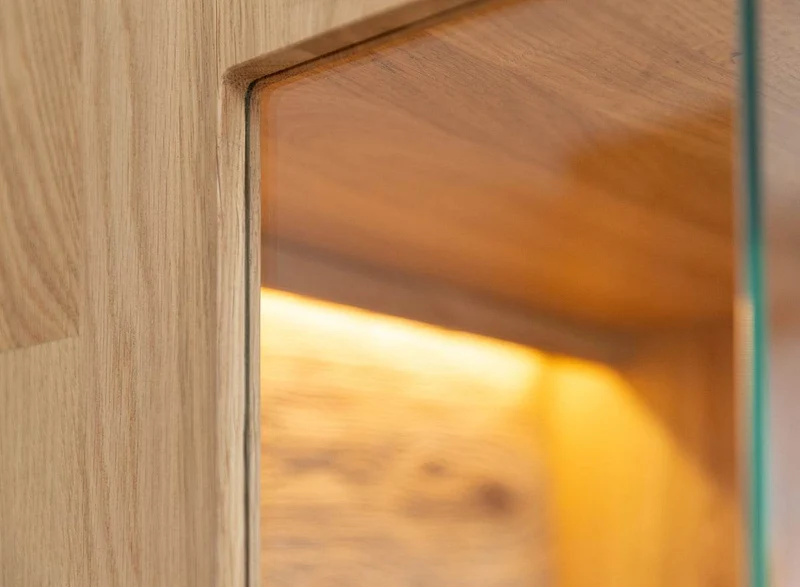 Beleuchtete Standvitrine aus massiver Eiche mit Lamellen | Wohnzimmerschrank Tirano II mit Rückwand in grober Holzstruktur